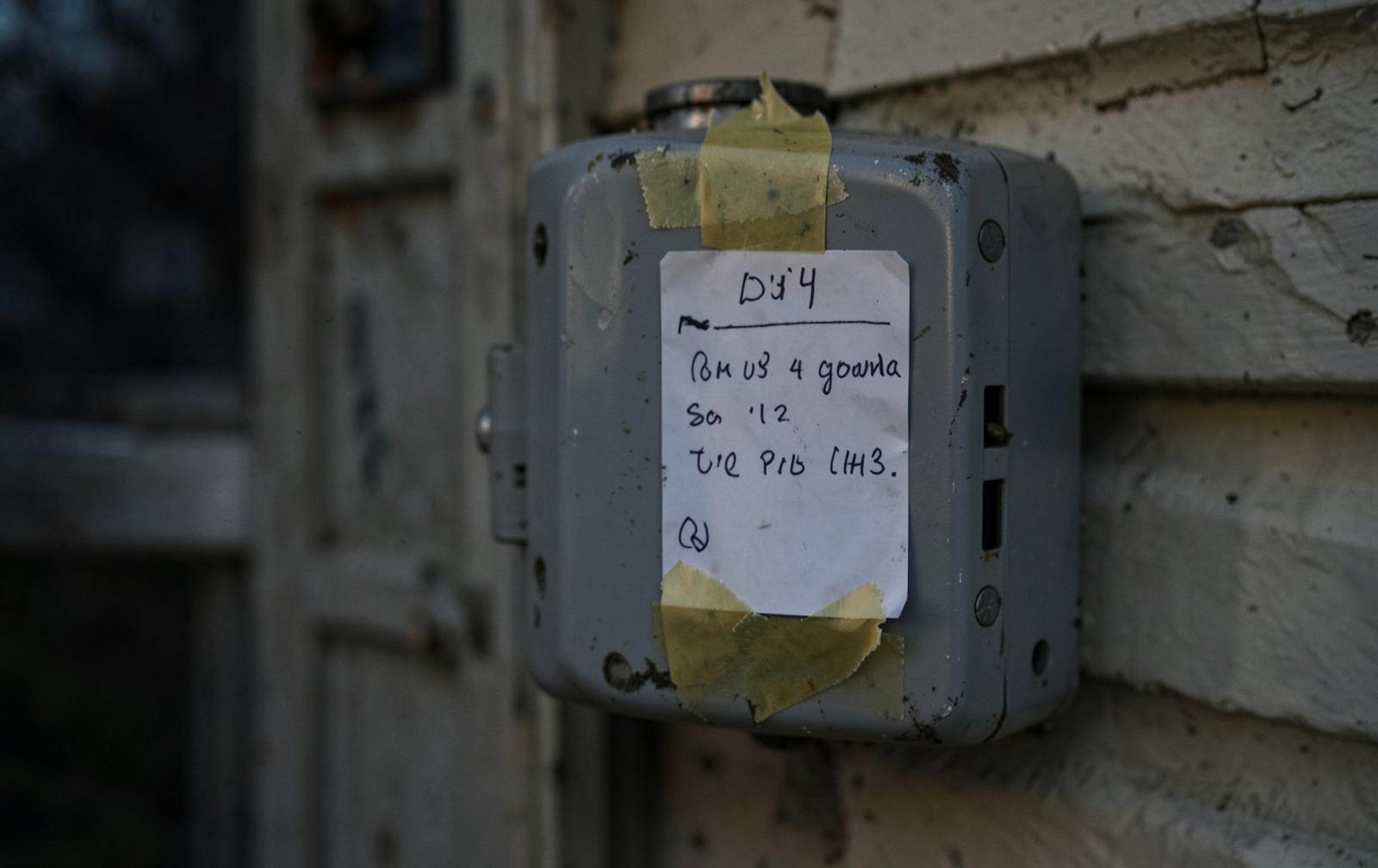 A handwritten index card taped to a residential electricity meter box